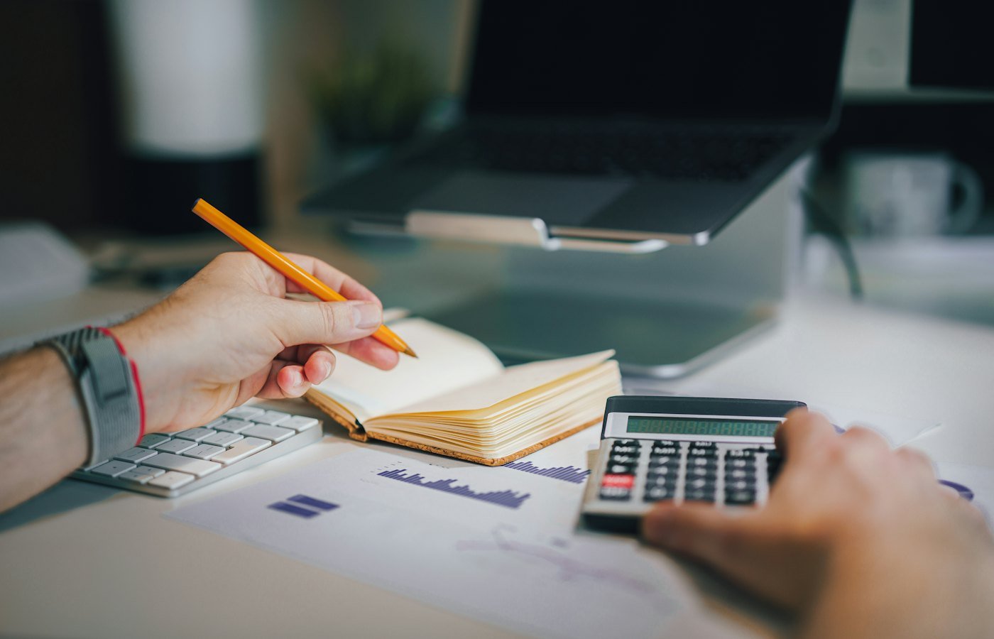 Pessoa sentada à mesa com calculadora e caderno planejando o orçamento